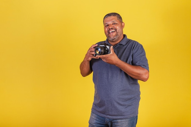 Homem negro brasileiro adulto segurando fotógrafo de hobby de fotografia de câmera fotográfica