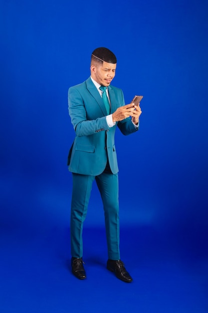 Homem negro brasileiro vestido de terno e gravata azul homem de negócios usando seu smartphone