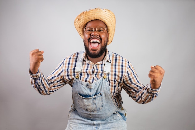 Homem negro brasileiro vestindo roupas country da festa junina festa de sao joao arraia comemorando