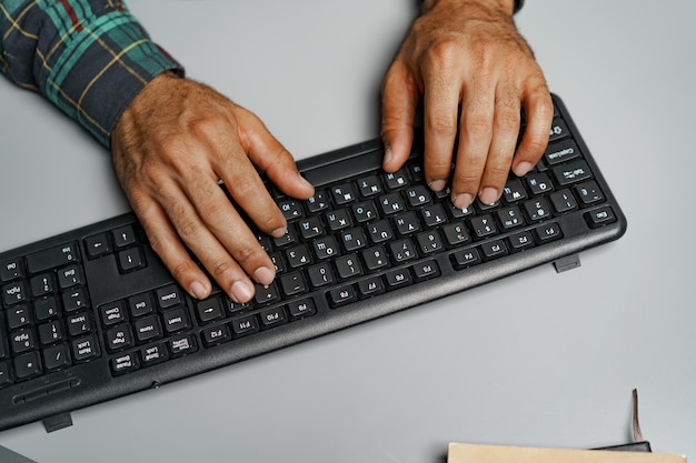 Homem negro com as mãos digitando no teclado do computador