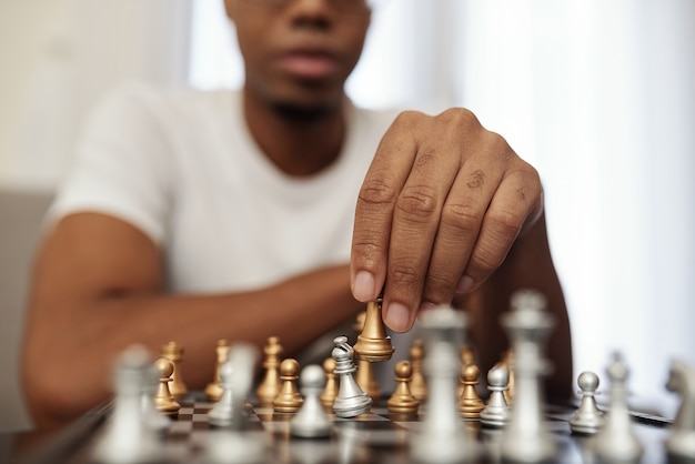 Homem negro concentrado e jovem jogando xadrez enquanto fica em casa durante a quarentena