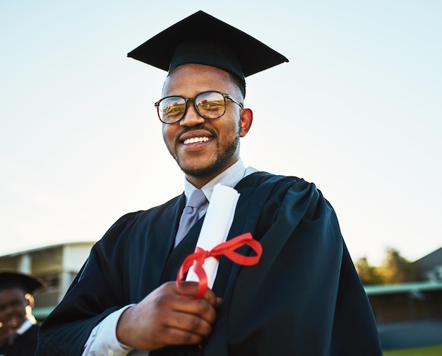 Homem negro da universidade e retrato com diploma na formatura por realização e sucesso de bolsa de estudos Céu do campus e estudante com certificado de honra por oportunidade de educação e prêmio acadêmico