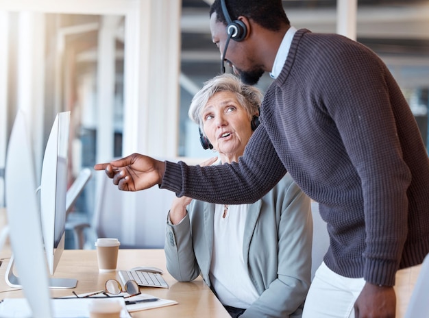 Homem negro de call center e funcionário de treinamento de treinadores em atendimento ao cliente ou suporte no escritório Gerente de telemarketing e trabalhador de coaching pessoal ou ajudando mulher sênior no computador com consultoria