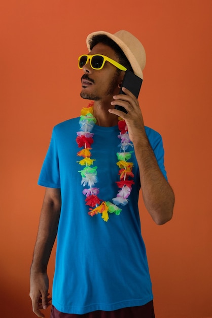 Homem negro em fantasia de carnaval segurando um telefone celular isolado em fundo laranja Homem africano em várias poses e expressões