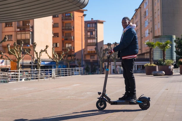 Homem negro étnico andando de skate em um skate elétrico verde e mobilidade limpa