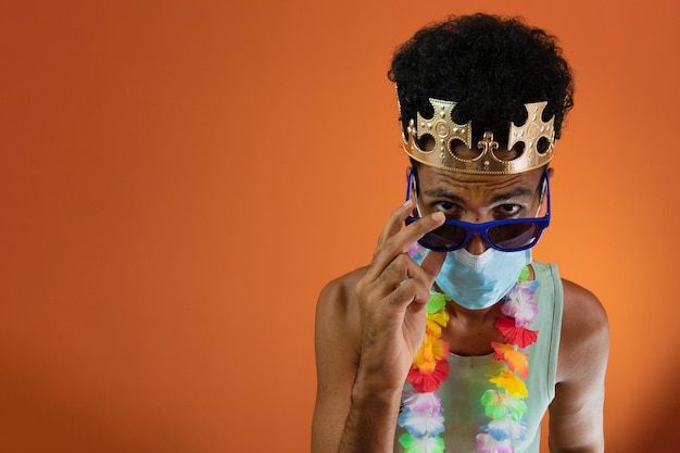 Homem negro fantasiado para carnaval com máscara pandêmica isolada em fundo laranja