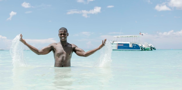 Homem negro feliz brincando com água do mar