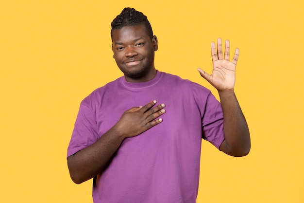 Homem negro honesto fazendo gesto de juramento posando sobre fundo amarelo
