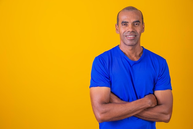 Foto homem negro mais velho cruzando os braços com confiança otimista feliz homem afro feliz com os braços cruzados em fundo amarelo