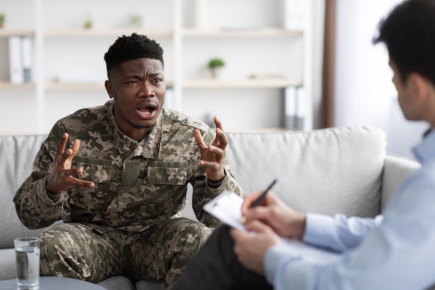 Homem negro militar emocional gesticulando enquanto conversava com psicoterapeuta