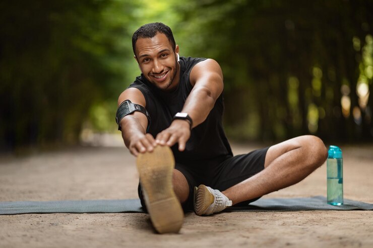 Foto homem negro musculoso positivo, estendendo-se no parque