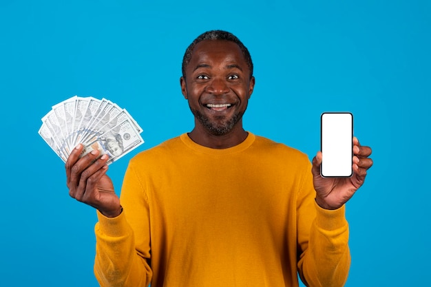 Homem negro positivo mostrando maquete de dinheiro e telefone celular