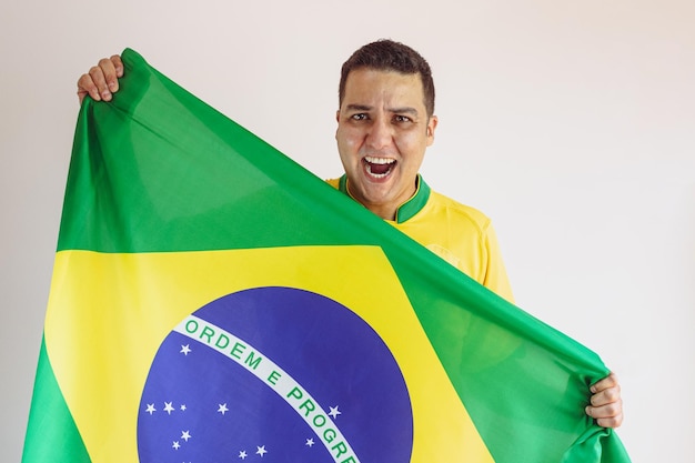 Homem negro segurando a bandeira brasileira com camisa amarela do time de futebol isolada no branco