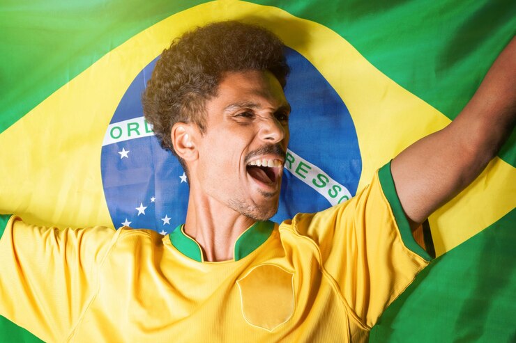 Foto homem negro segurando a bandeira do brasil atrás de comemorar