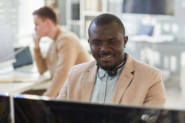 Homem negro sorridente olhando para o computador no centro de atendimento ao cliente