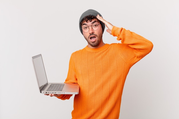 Homem nerd com computador parecendo feliz, espantado e surpreso, sorrindo e percebendo uma boa notícia incrível