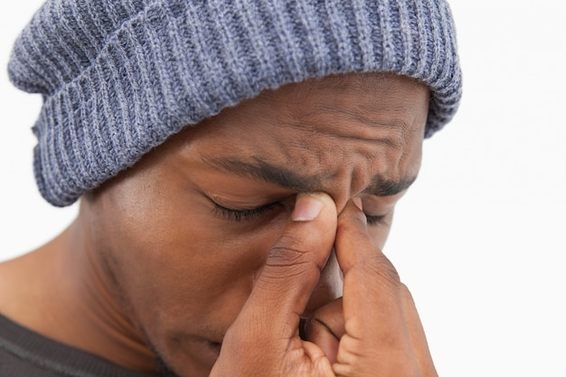 Homem no chapéu do chapéu beanie com uma dor de cabeça