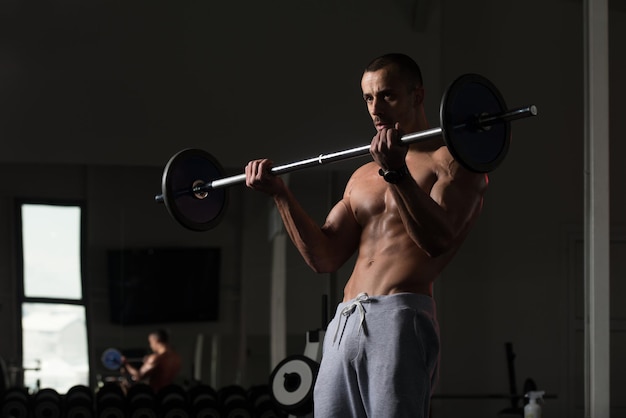 Homem no ginásio exercitando bíceps com barra