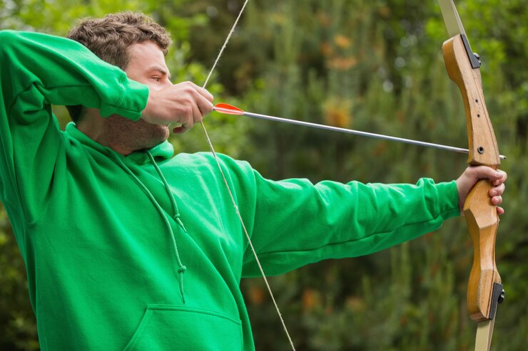 Foto homem no jumper verde prestes a atirar flecha