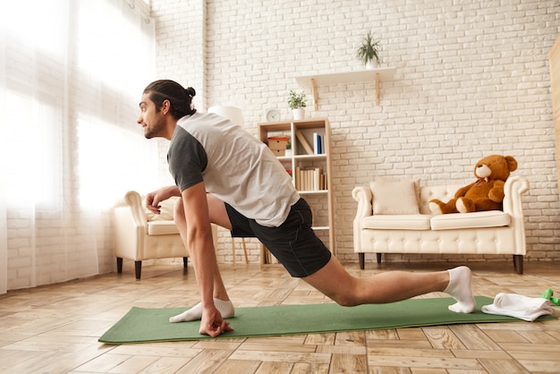 Homem no sportswear está tendo dentro de casa o treino.