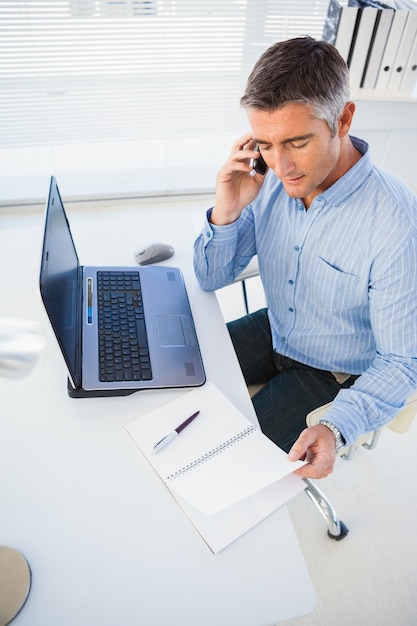 Homem no telefone e olhando no caderno