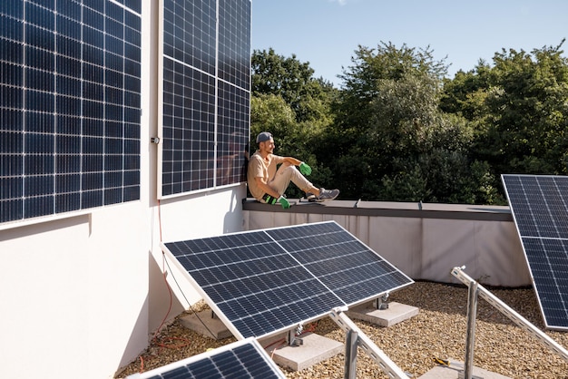 Foto homem no telhado de sua casa com uma usina solar