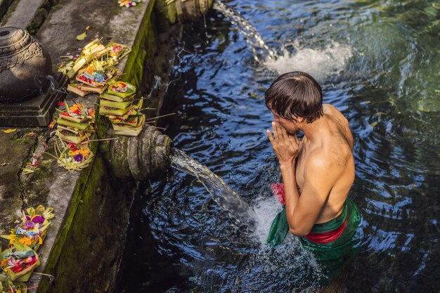 Homem no templo de água de nascente em bali O complexo do templo consiste em um petrtaan ou estrutura de banho famosa por sua água de nascente sagrada