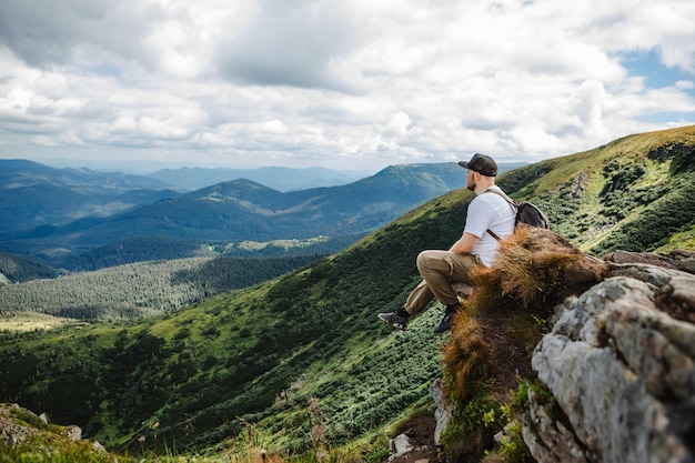 Homem no topo de uma montanha sentado em uma rocha