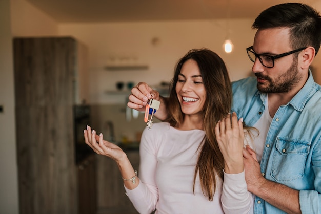 Homem novo atrativo que surpreende sua esposa com uma chave a seu apartamento novo.