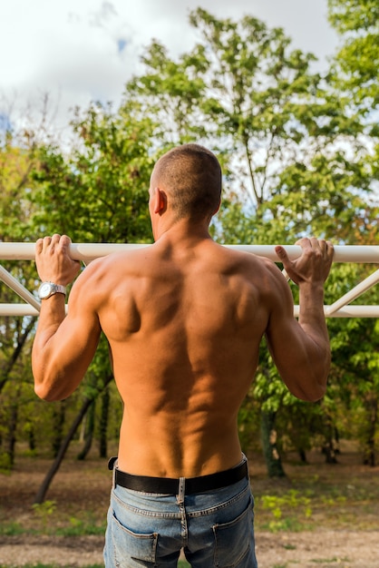 Homem novo muscular durante seu exercício na rua. Fit, fitness, treino, exercício