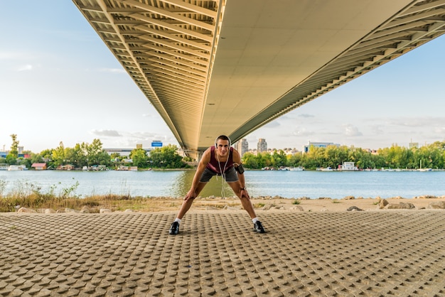 Homem novo muscular durante seu exercício na rua.