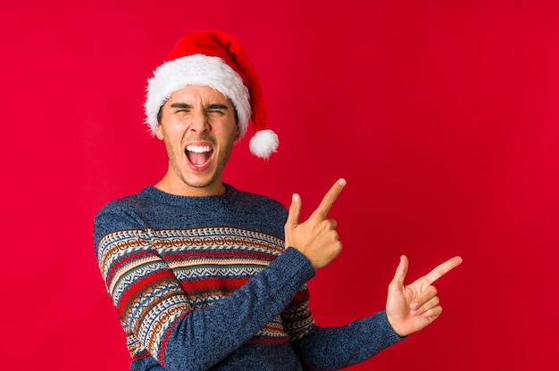 Homem novo no dia de Natal que olha esquerdo, pose lateral.