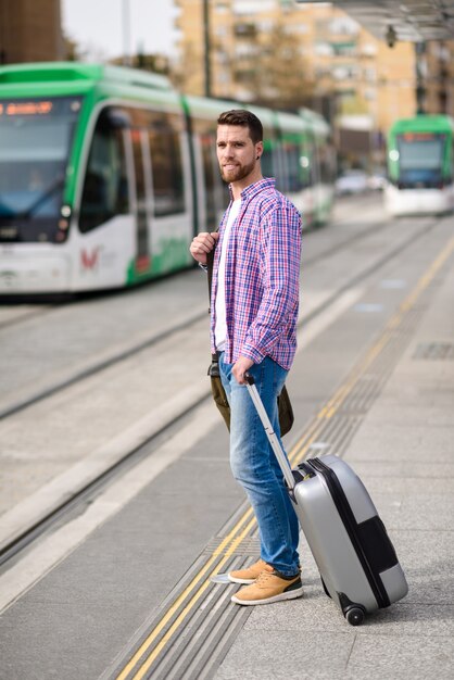 Homem novo que espera seu trem na estação de metro urbana. conceito de estilo de vida.