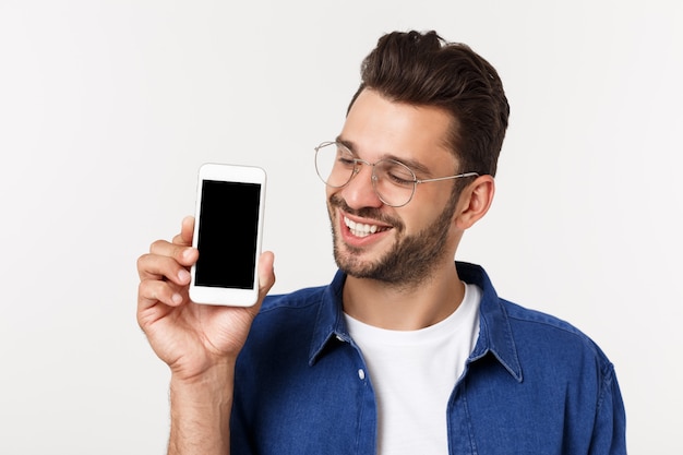 Homem novo que mostra seu telefone esperto brandnew isolado no branco.