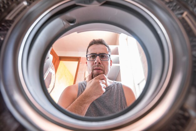 Homem novo que quer saber como a máquina de lavar roupa trabalha.