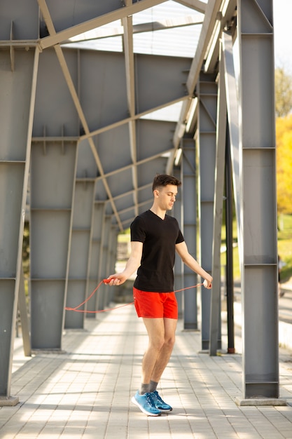 Homem novo que salta com corda de salto ao ar livre. Exercício e estilo de vida.