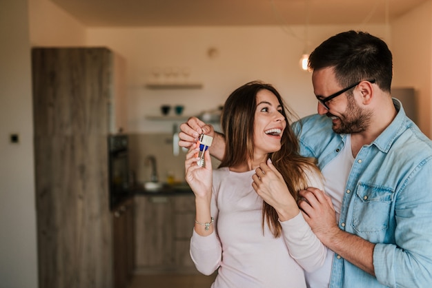 Foto homem novo que surpreende sua esposa ou uma menina com o apartamento novo.