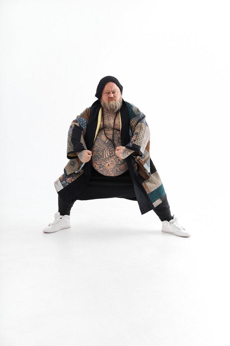Foto homem obeso, barbudo e tatuado, com uma barriga grande posando e dançando de quimono
