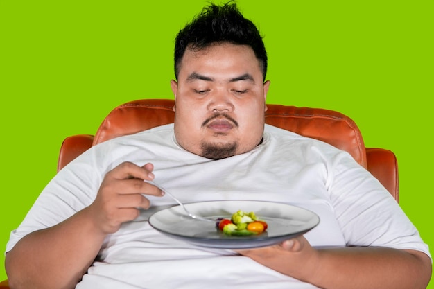 Homem obeso parece hesitar em comer salada no estúdio