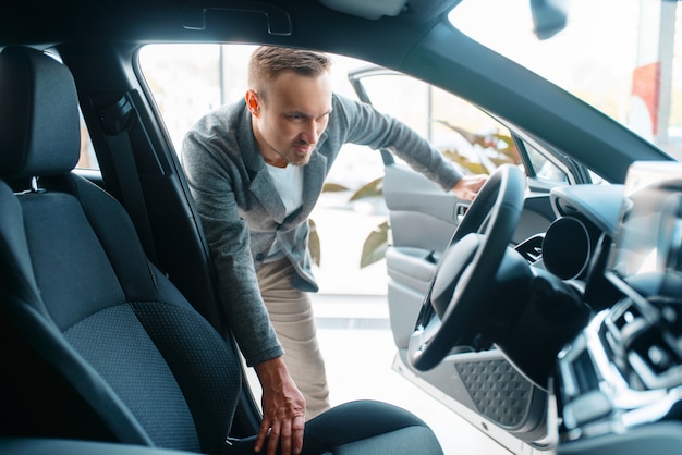 Homem observando o interior de um carro novo no showroom