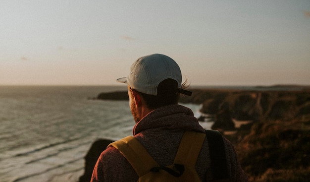 Homem observando o pôr do sol de um penhasco