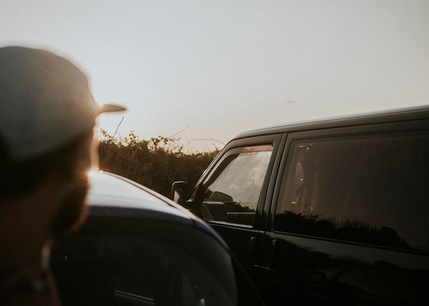 Homem observando o pôr do sol em seu jipe