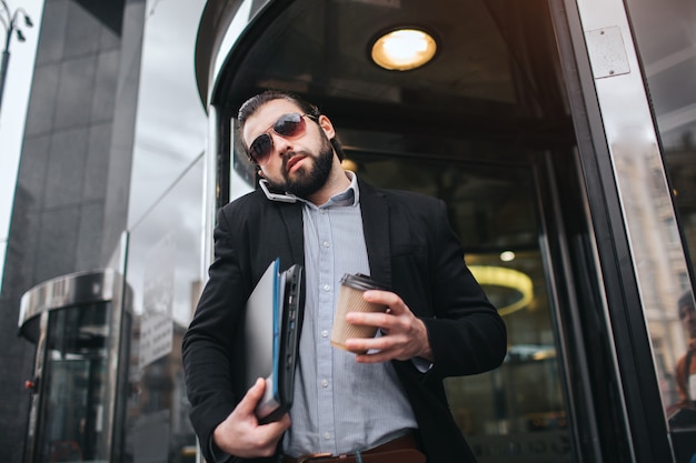 Homem ocupado está com pressa, ele não tem tempo, ele vai falar ao telefone em qualquer lugar. Empresário, fazendo várias tarefas. Pessoa de negócios multitarefa.