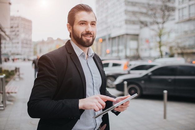 Homem ocupado está com pressa, ele não tem tempo, ele vai usar o tablet pc em movimento. Empresário, fazendo várias tarefas. Pessoa de negócios multitarefa.