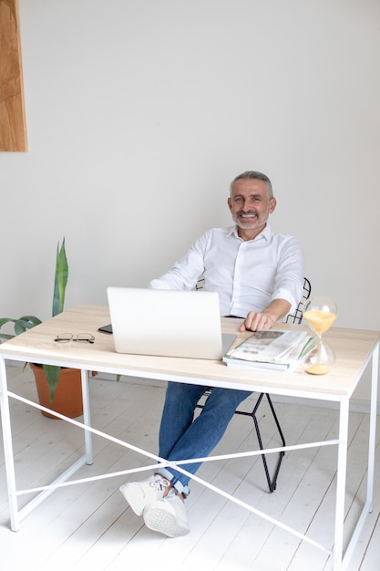 Homem olhando para a câmera sentado na mesa no escritório