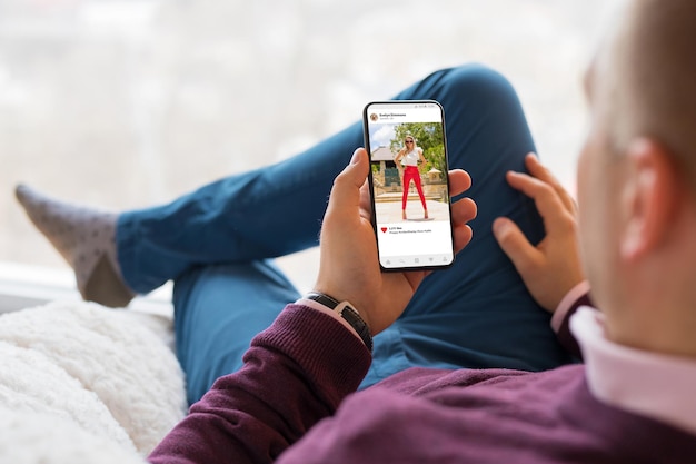 Homem olhando para aplicativo de compartilhamento de fotos no celular