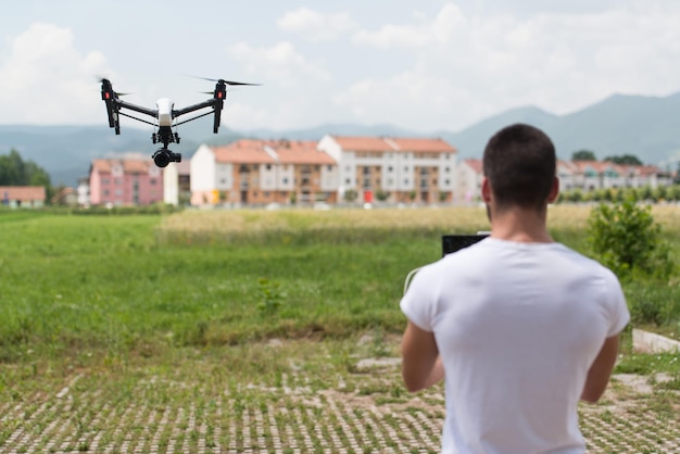 Homem operando drone voando ou pairando por controle remoto na natureza