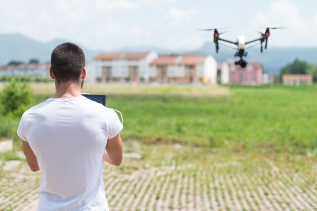 Homem operando drone voando ou pairando por controle remoto na natureza