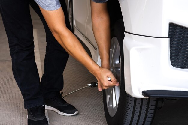 Homem ou trabalhador mecânico de automóveis trocar o pneu do carro ou fazer a manutenção antes de viajar por questões de segurança.