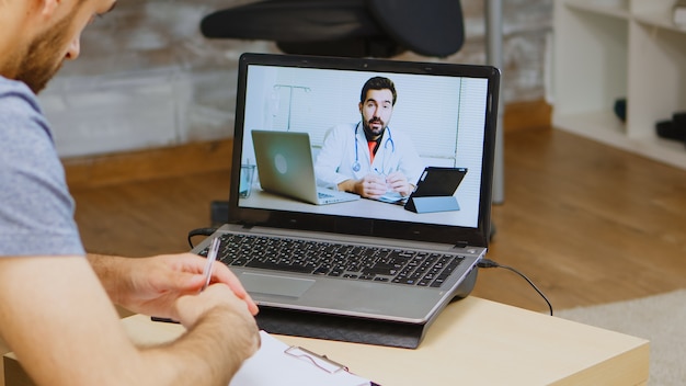 Homem ouvindo conselhos do médico na chamada de vídeo durante o isolamento global.